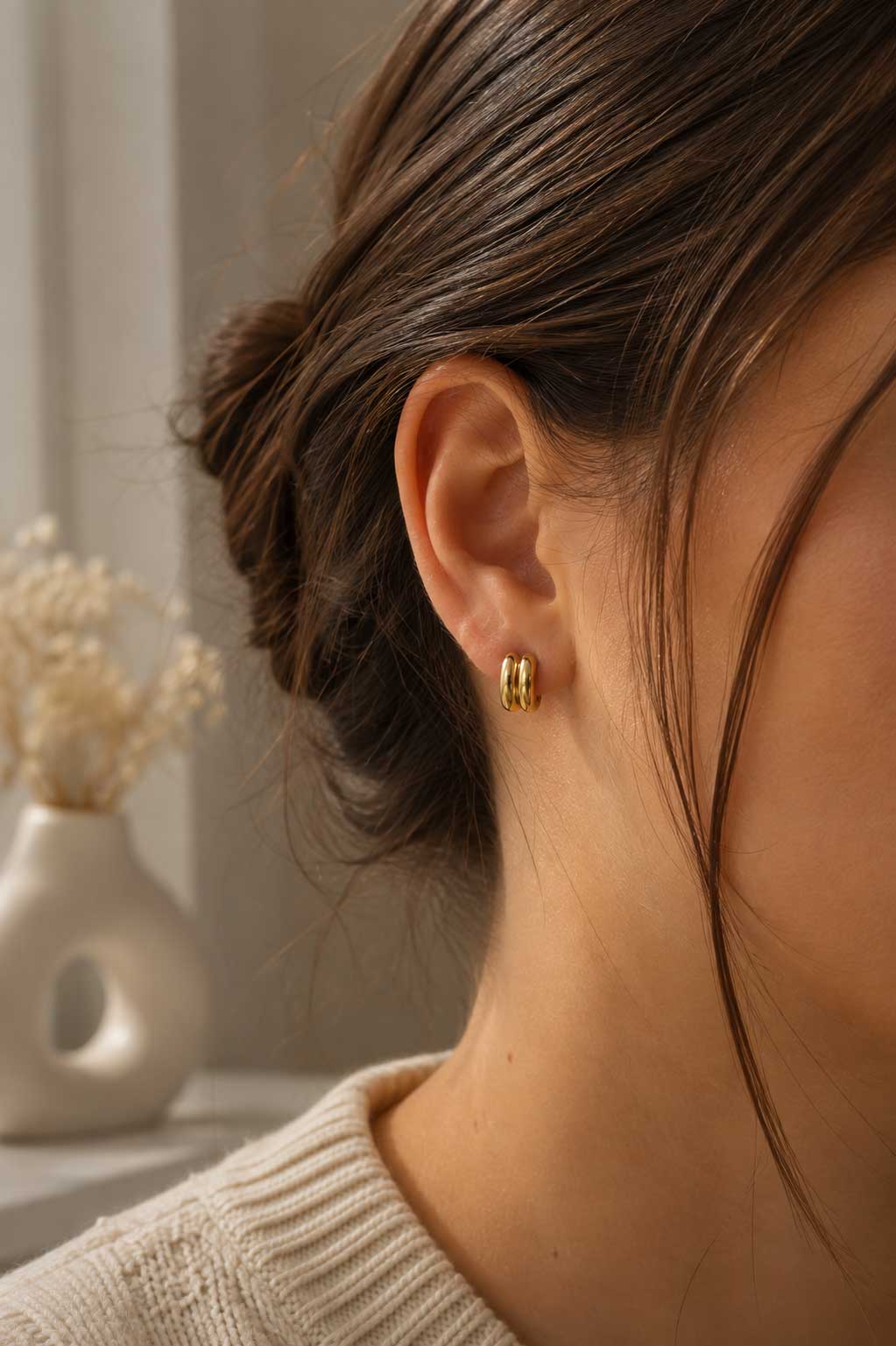 Brünette Frau mit hochgestecktem Haar trägt goldene Curve Ohrringe – elegante Lifestyle-Aufnahme – Saltyblush
