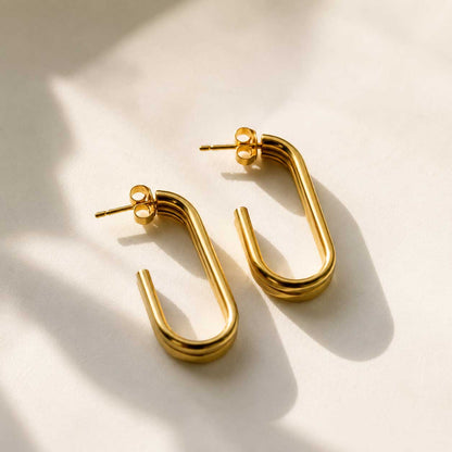 Goldene U-förmige Ohrringe mit doppeltem Steg aus Edelstahl auf cremefarbenem Hintergrund – Golden Curve U-Shape von Saltyblush
