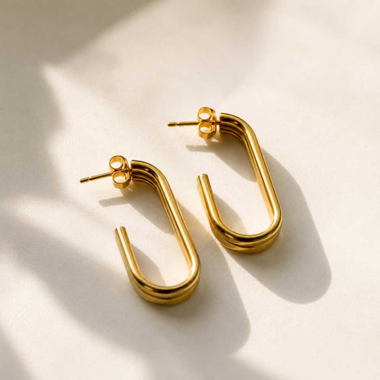 Goldene U-förmige Ohrringe mit doppeltem Steg aus Edelstahl auf cremefarbenem Hintergrund – Golden Curve U-Shape von Saltyblush
