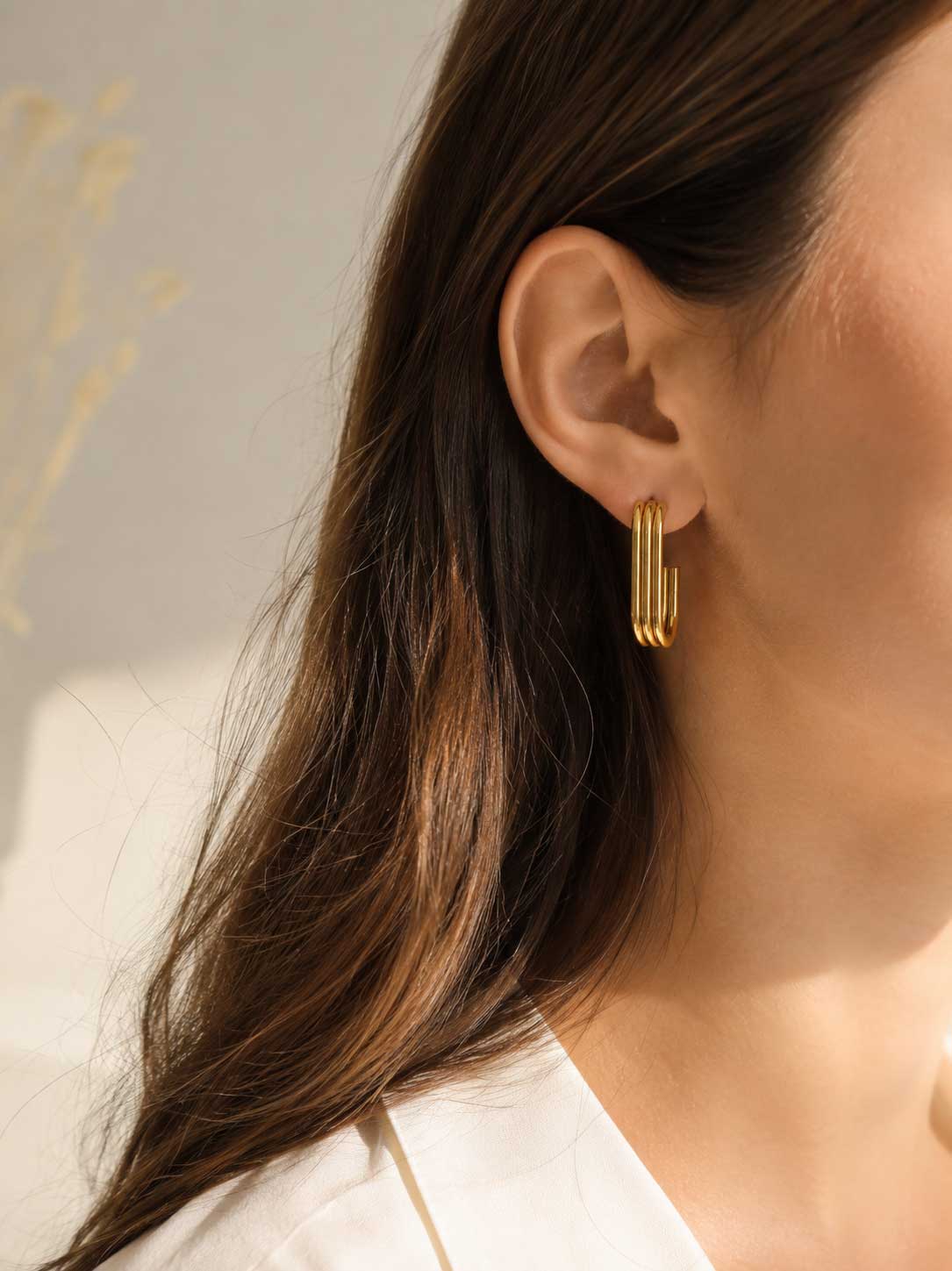 Golden Curve U-Shape goldene Ohrringe am Ohr getragen mit offenem dunklem Haar und weißem Blazer – Saltyblush
