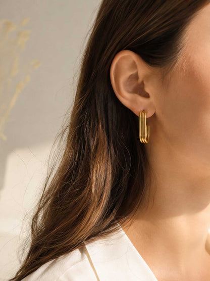 Golden Curve U-Shape goldene Ohrringe am Ohr getragen mit offenem dunklem Haar und weißem Blazer – Saltyblush
