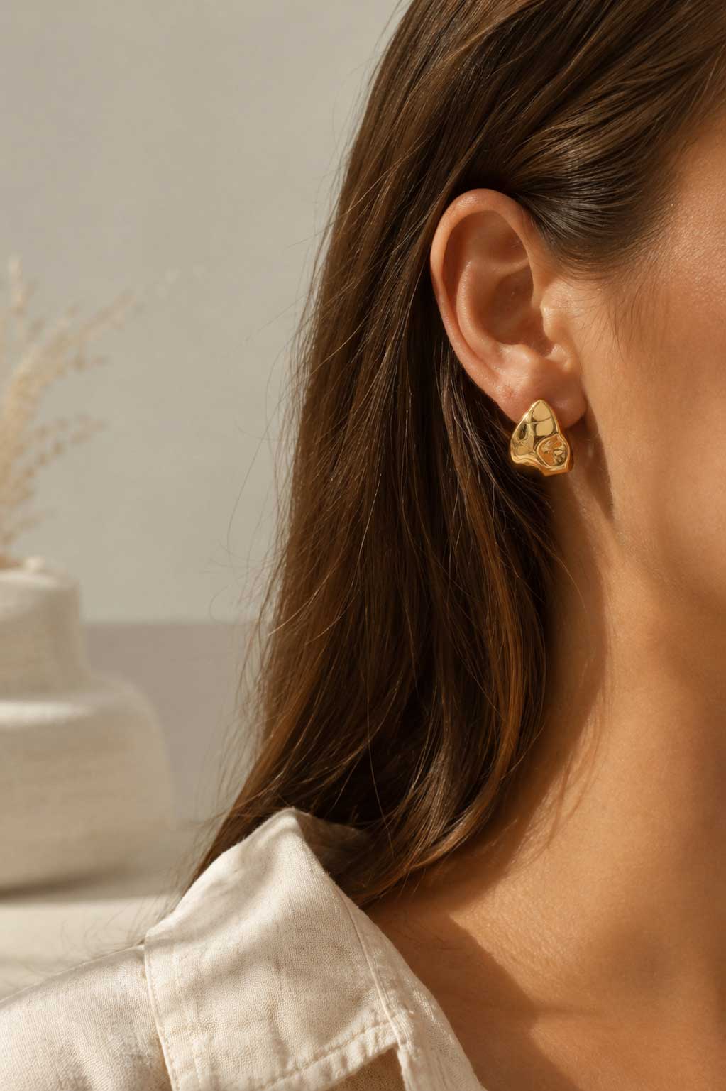 Brünette Frau trägt goldene Drop Ohrstecker mit braunem Stein am Ohr – Lifestyle-Aufnahme – Saltyblush

