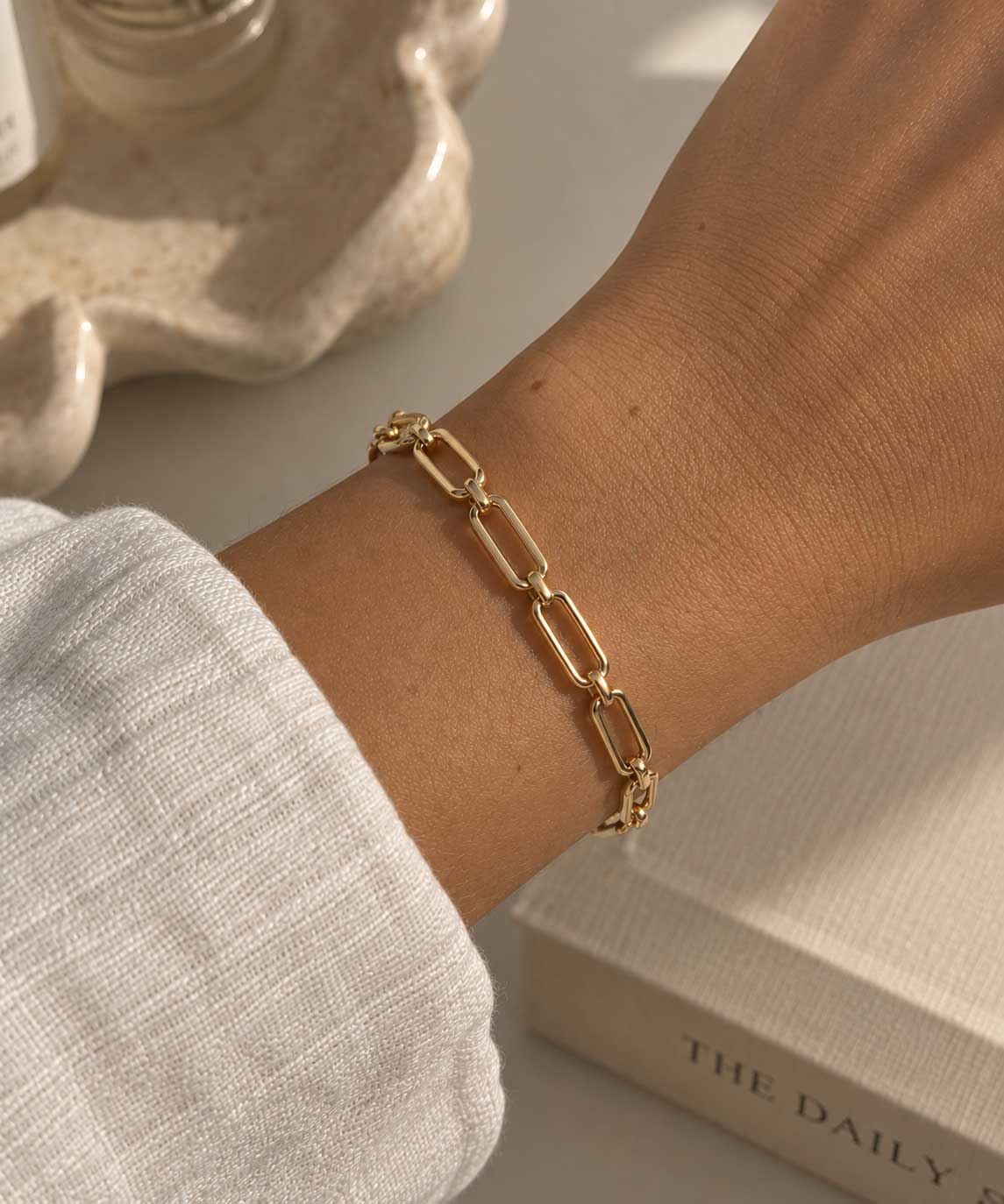 Goldenes Gliederarmband aus Edelstahl am Handgelenk getragen, mit offenen Gliedern und verstellbarer Länge für elegante Alltags- und Layering-Looks
[AI]