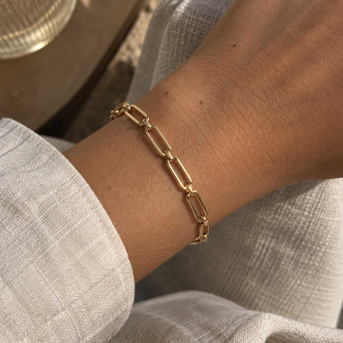 Goldenes Gliederarmband aus Edelstahl am Handgelenk getragen, mit offenen Gliedern und verstellbarer Länge für elegante Alltags- und Layering-Looks
[AI]