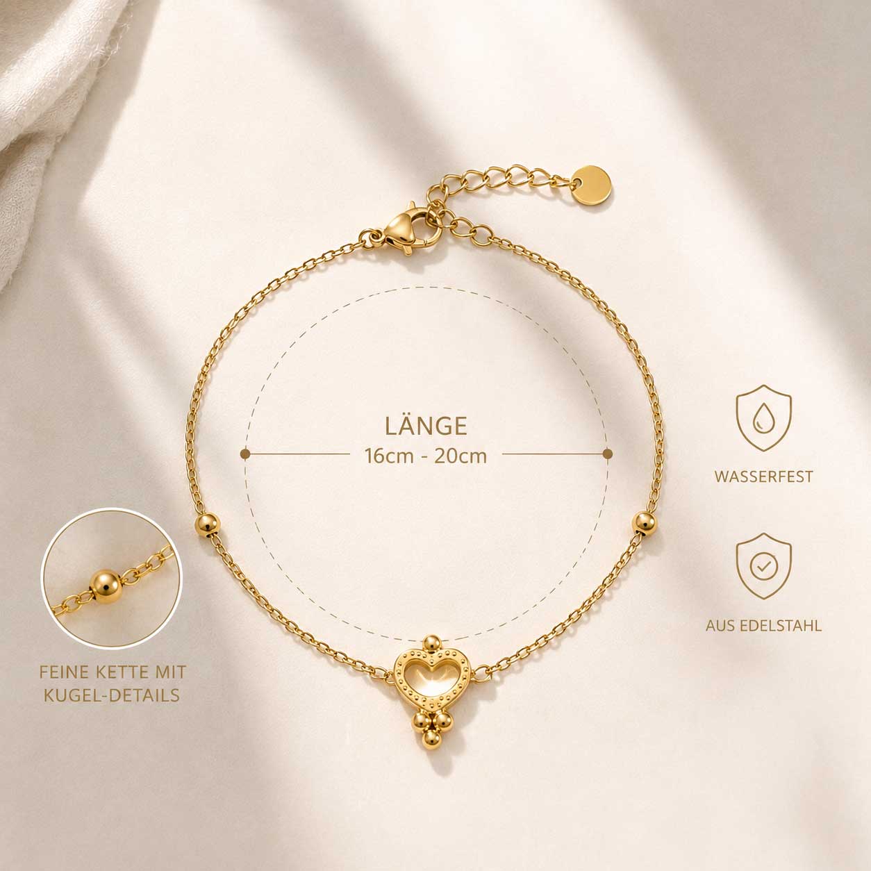 Nahaufnahme goldener Herzanhänger – Golden Glow Armband von Saltyblush, offenes Herz mit Kugelrand und 3 Kugelanhängern, Detailansicht auf weißem Stoff

