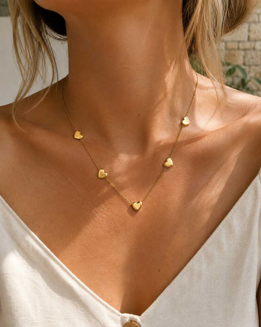 Golden Heart Halskette Lifestyle – goldene Herzhalskette von Saltyblush, getragen im Sonnenlicht, romantischer Layering-Look
