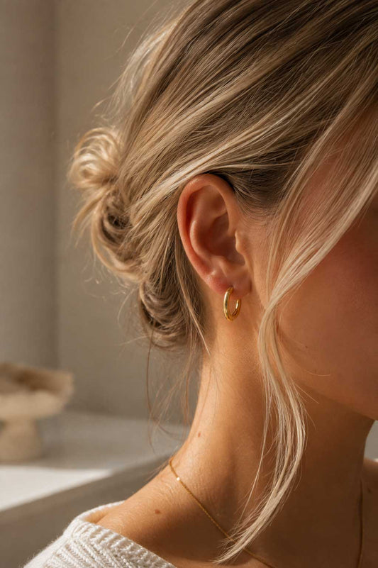 Blonde Frau mit hochgestecktem Haar trägt goldene Hoop Ohrringe aus Edelstahl – elegante Lifestyle-Aufnahme – Saltyblush

