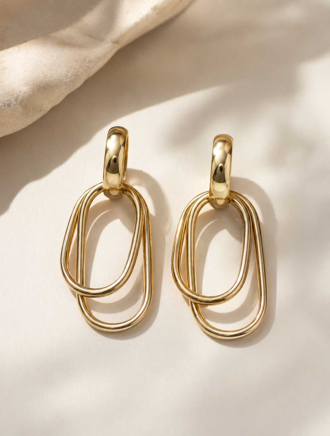 Goldene Ohrringe mit doppelten ovalen Ringen auf hellem Hintergrund – Golden Loop von Saltyblush
