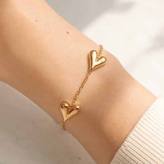 Goldenes Herzarmband am Handgelenk getragen, vergoldete Herz-Charms auf feiner Gliederkette
