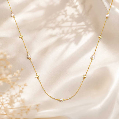 Golden Pearl Halskette Flatlay – goldene Perlenkette von Saltyblush, filigrane Goldkette mit 5 weißen Perlen und goldenen Plättchen, auf weißem Stoff mit Trockenblumen
