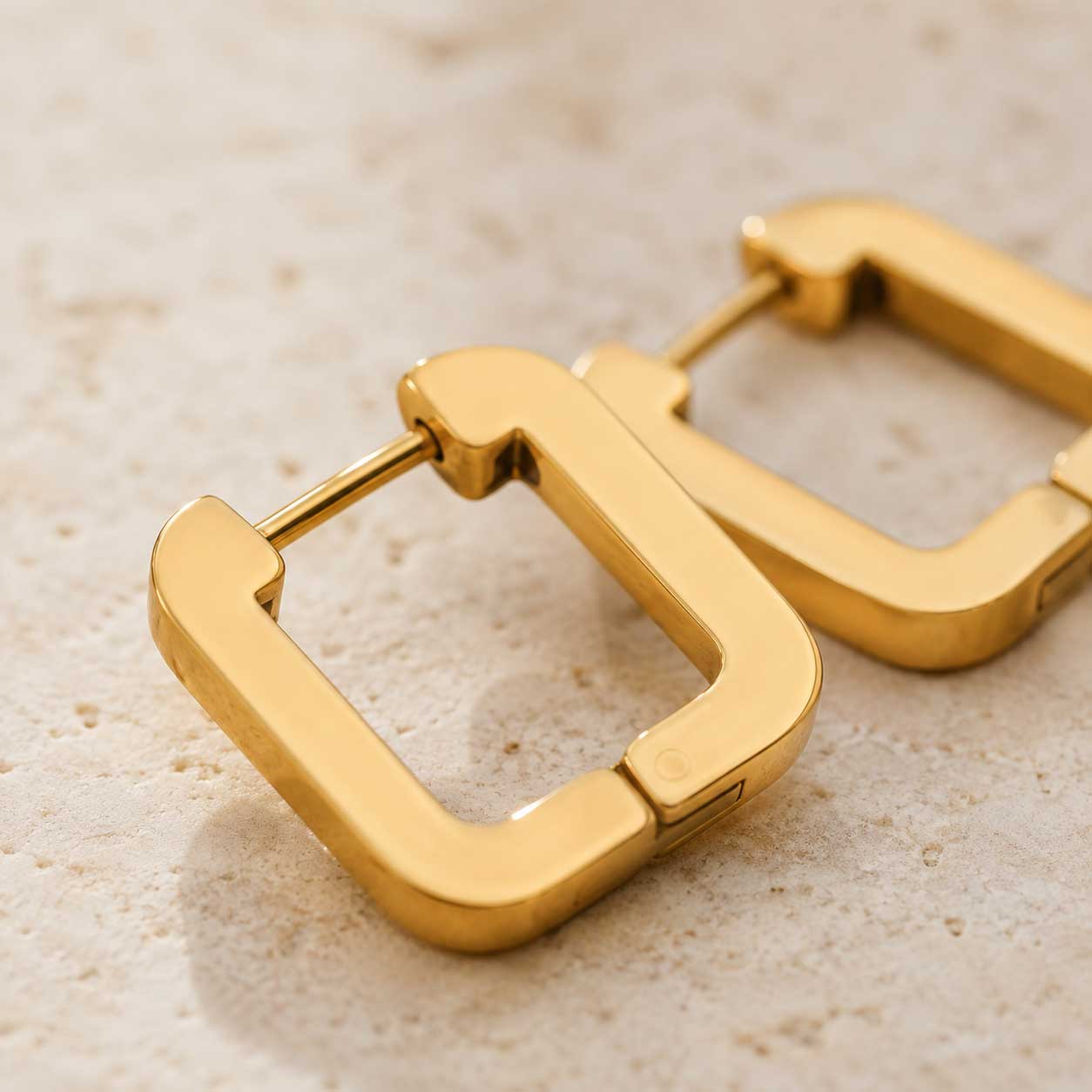 Nahaufnahme goldener viereckiger Creolen aus Edelstahl – Detail des Klappverschlusses – Saltyblush
