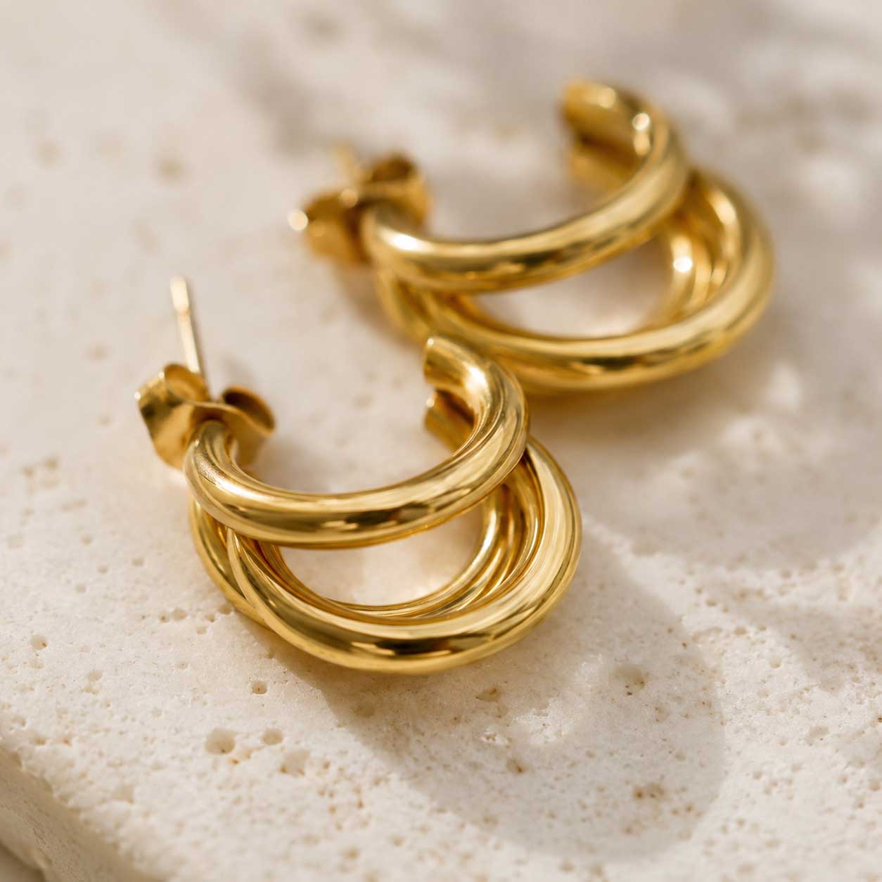 Nahaufnahme goldener dreilagiger Creolen mit glänzender Wellenstruktur aus Edelstahl – Golden Wave Hoops von Saltyblush
