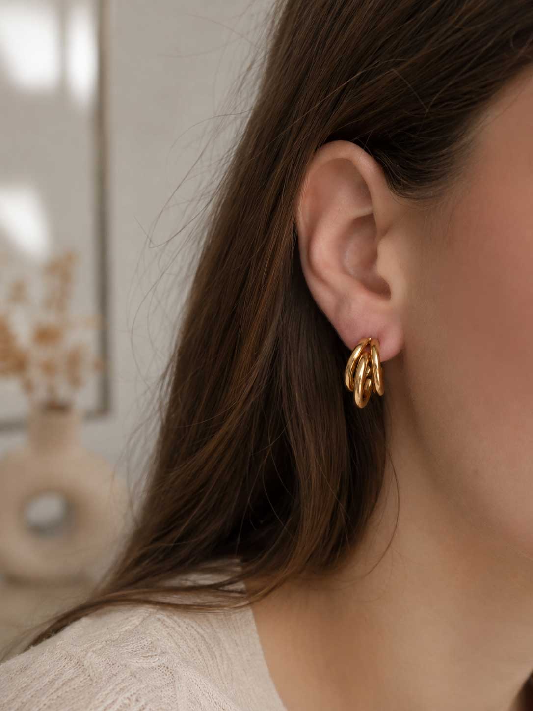 Golden Wave Hoops goldene dreilagige Creolen am Ohr getragen mit offenem dunklem Haar und weißem Top – Saltyblush
