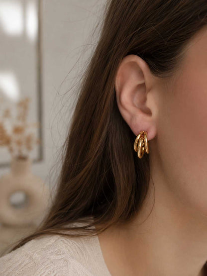 Golden Wave Hoops goldene dreilagige Creolen am Ohr getragen mit offenem dunklem Haar und weißem Top – Saltyblush
