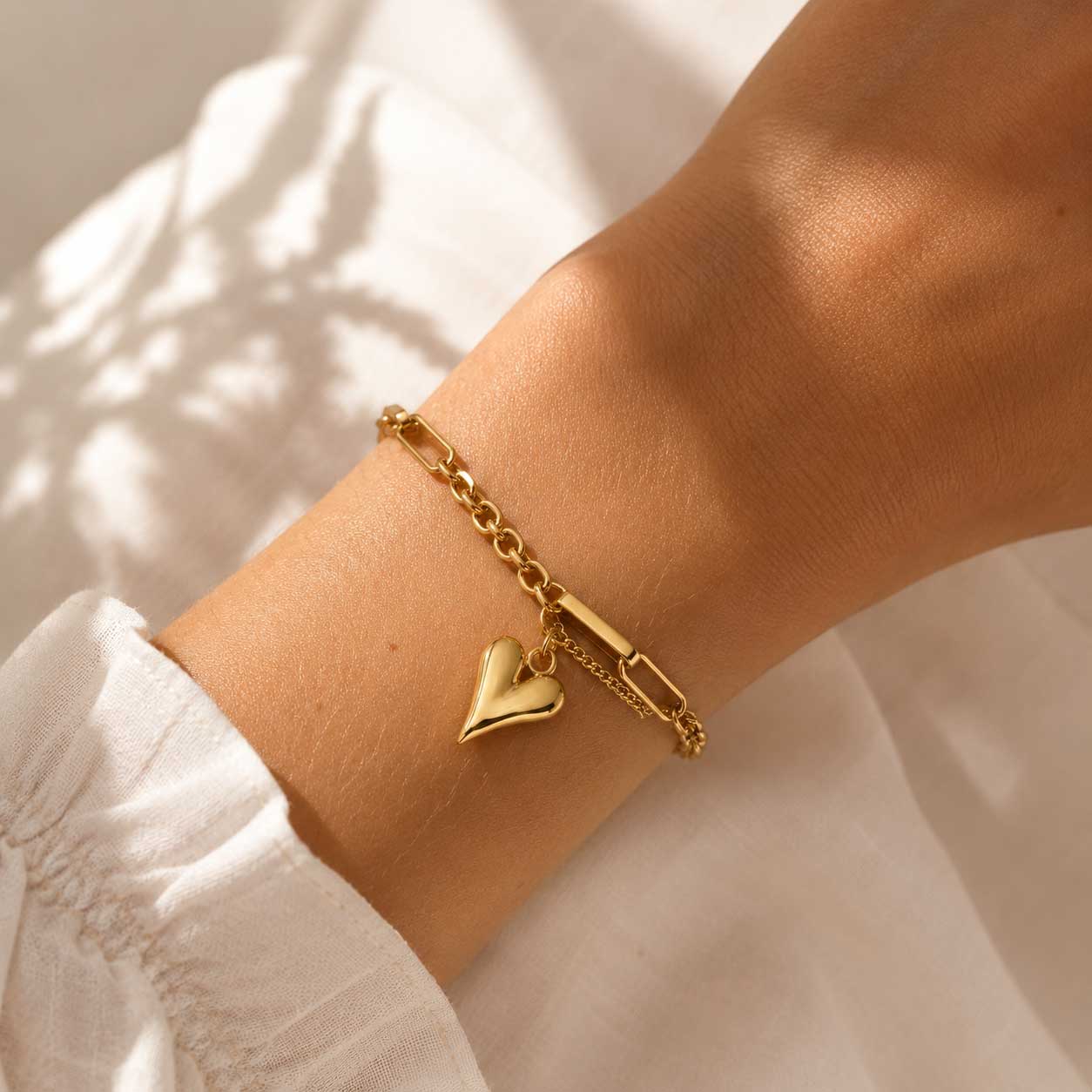 Heartwave Armband am Handgelenk – goldenes Herzarmband von Saltyblush getragen, zweireihige Kette mit Herzcharm zu weißem Outfit
