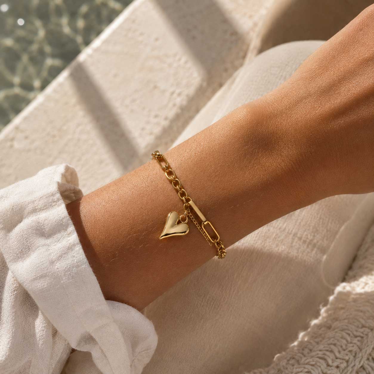 Heartwave Armband Lifestyle – goldenes Herzarmband von Saltyblush am Handgelenk, sommerlicher Look am Wasser, elegantes Schmuckstück
