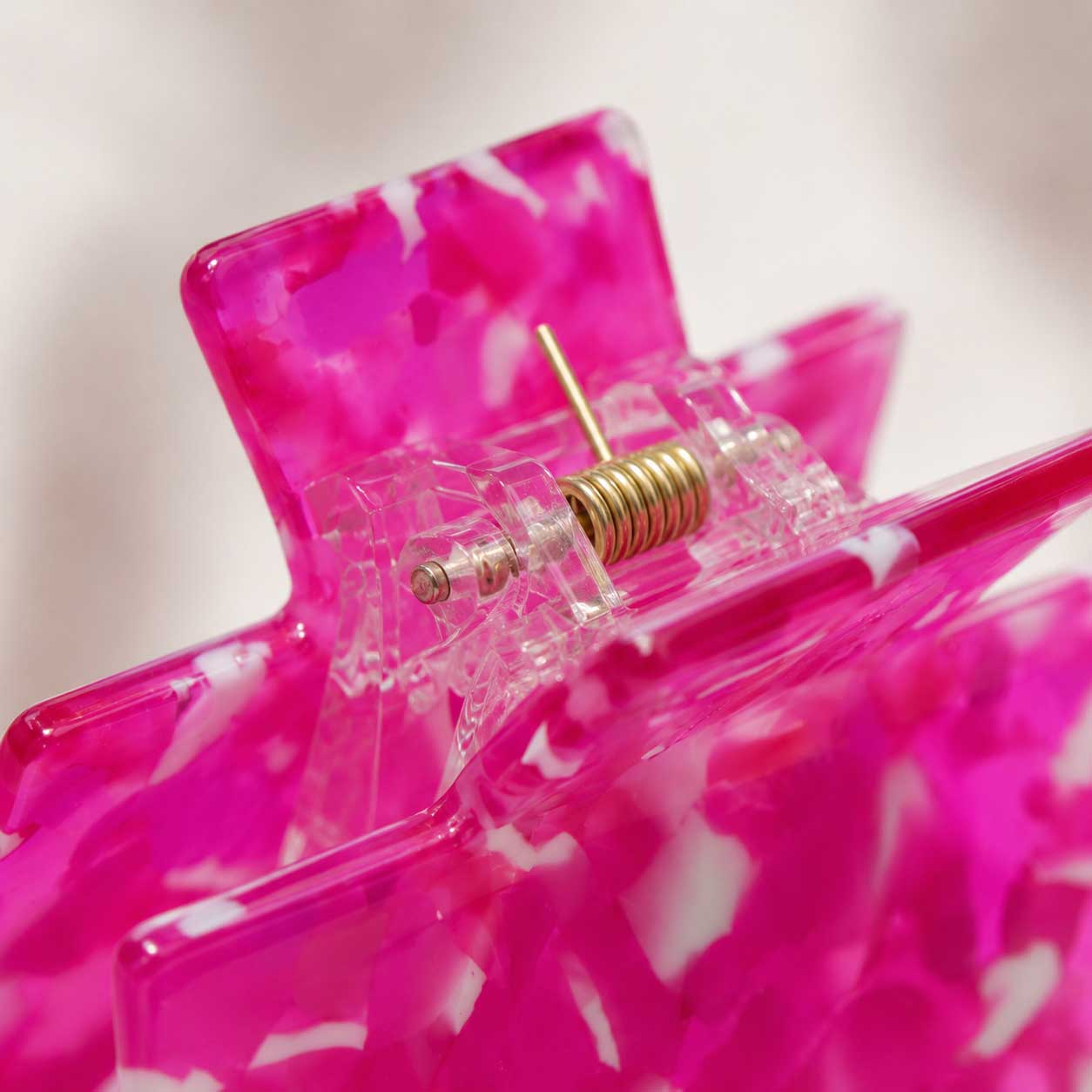Nahaufnahme des goldenen Federmechanismus der Hot Pink Crush Haarklammer aus transparentem Acryl – Saltyblush
