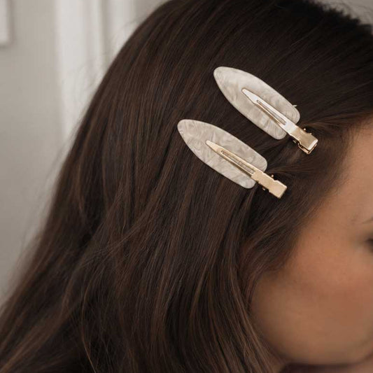 Ivory Pearl Haarclips getragen im dunklen Haar – marmorierte Haarklammern mit Golddetail
