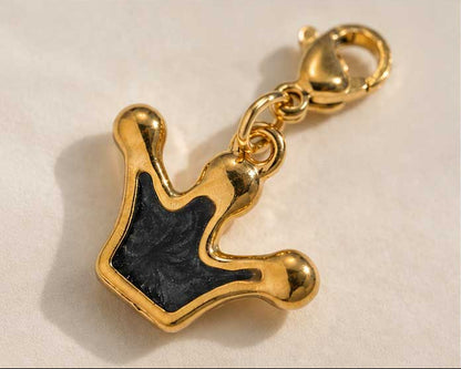 Nahaufnahme goldener Kronen-Charm mit schwarzer Emaille-Füllung und Karabinerverschluss – Edelstahl – Saltyblush
