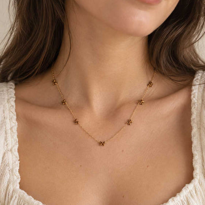 Goldene Halskette aus Edelstahl mit Schleifenanhänger am Hals getragen, zarter Schmuck für feminine Alltagslooks und elegante Layering-Kombinationen
[AI]