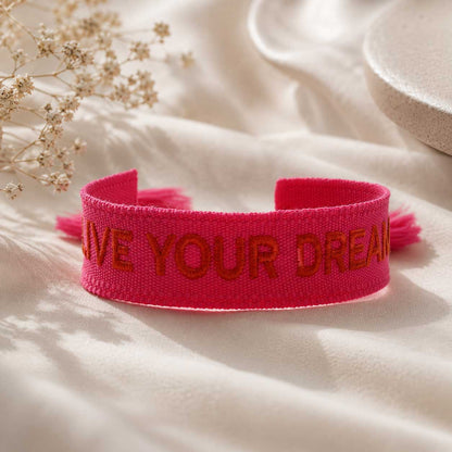 Pinkes Statement Armband mit roter Live Your Dreams Aufschrift auf weißem Stoff, Draufsicht – Saltyblush
