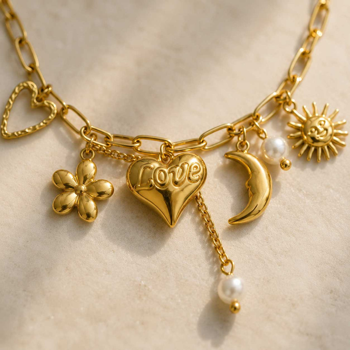 Nahaufnahme goldener Charm-Anhänger Herz, Sonne, Mond und Perlen an Gliederkette – Love & Light Armband von Saltyblush
