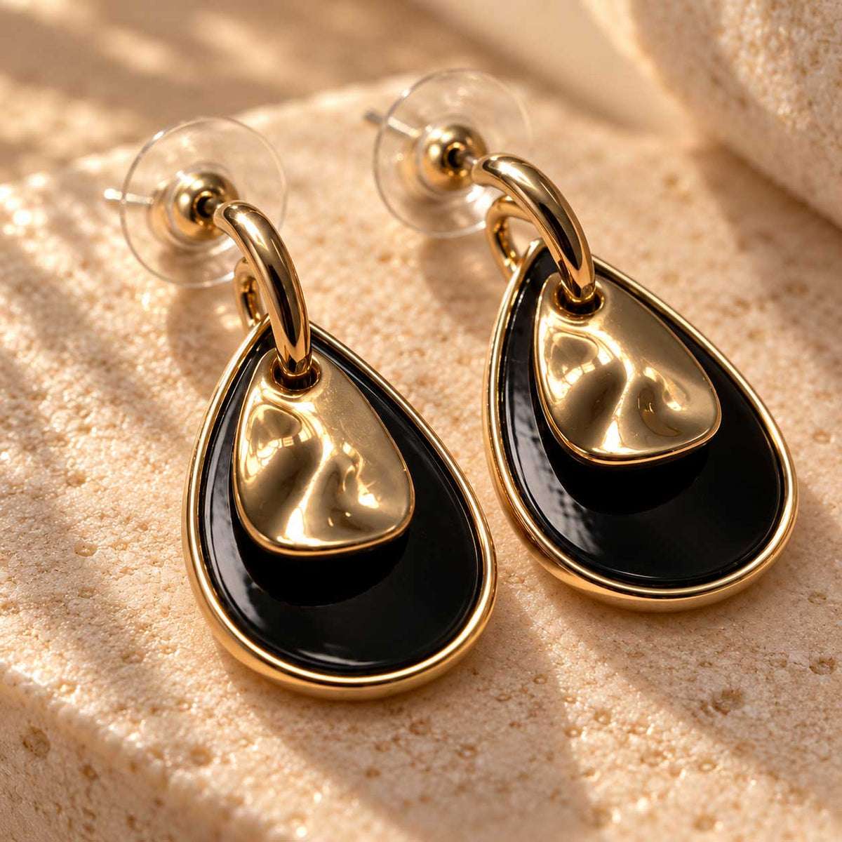 Nahaufnahme: schwarzes Tropfen-Element an goldenen Edelstahl-Ohrsteckern midnight drop
