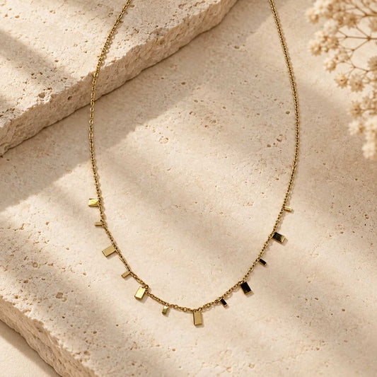 Goldene Halskette mit rechteckigen Plättchen – Minimalist Chic Halskette von Saltyblush, filigrane Goldkette mit 11 kleinen Rechteck-Charms, Flatlay auf hellem Hintergrund
