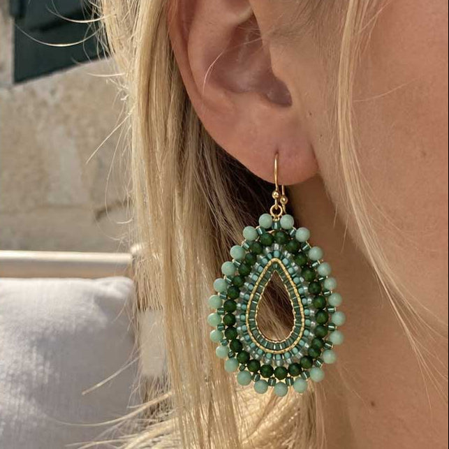 Goldene Perlenohrringe aus Edelstahl an einer Person getragen, mit facettierten Glasperlen in Mint und Grün, filigraner Tropfenform und auffälligem Boho-Design
