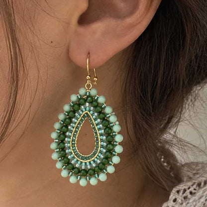 Goldene Perlenohrringe aus Edelstahl an einer Person getragen, mit facettierten Glasperlen in Mint und Grün, filigraner Tropfenform und auffälligem Boho-Design
