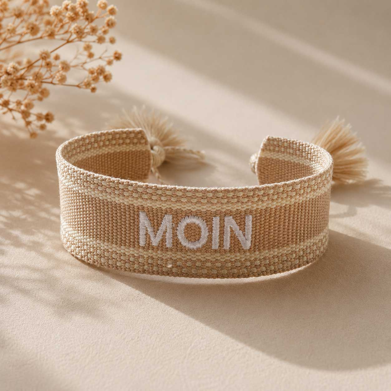 Beiges Statement Armband mit weißer MOIN Stickerei und cremefarbenen Quasten, Draufsicht mit Trockenblumen – Saltyblush
