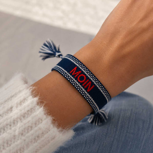Statement Armband MOIN in Dunkelblau am Handgelenk getragen mit weißem Strickpullover – Saltyblush
