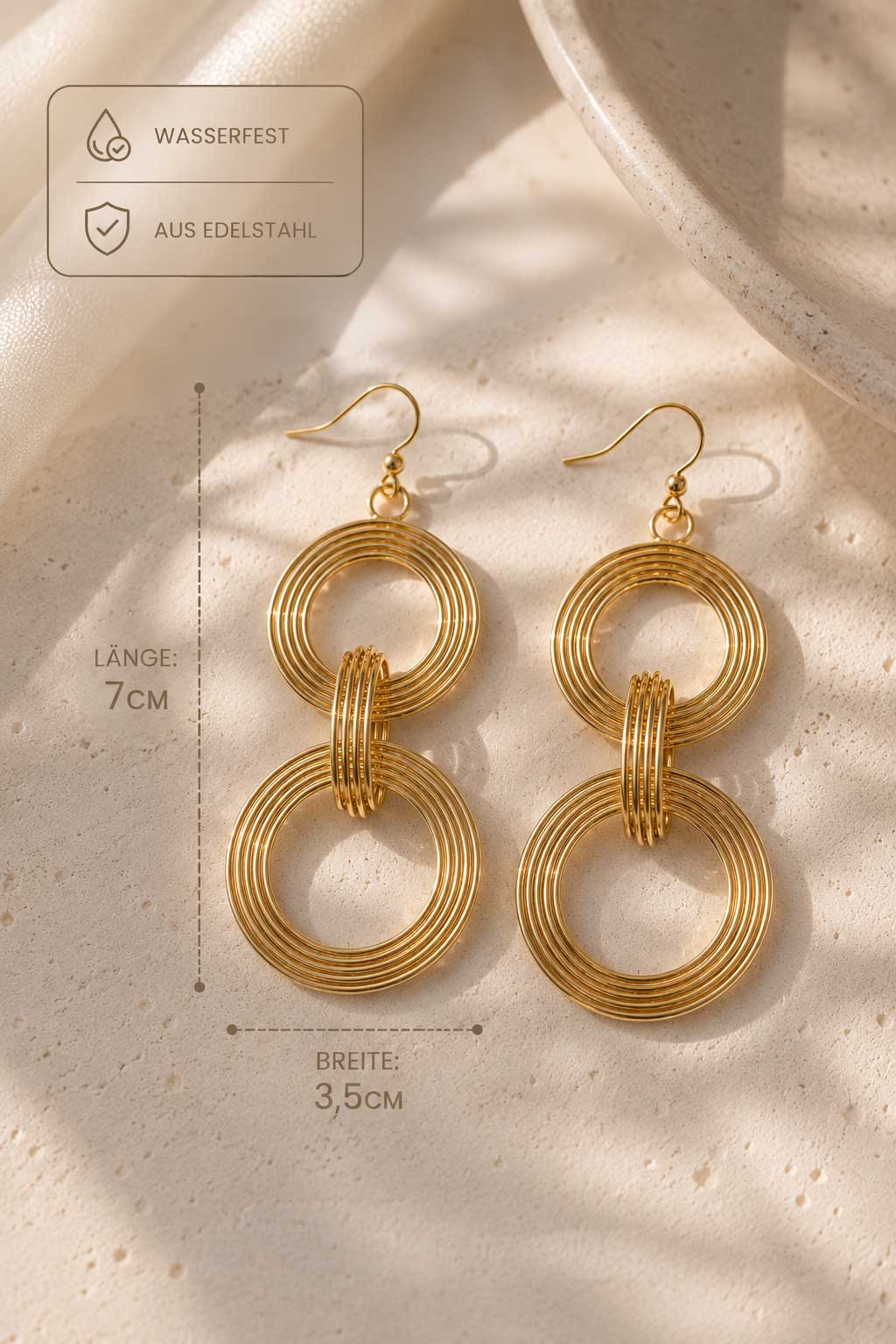 Goldene Doppelring-Ohrhänger Infografik – gerippte Kreisohrringe Länge 7 cm, Breite 3,5 cm, wasserfest, aus Edelstahl auf cremefarbenem Seidenstoff
