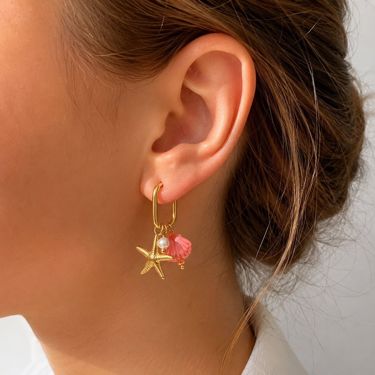 Goldene Creolen Pearl and Sea mit Seestern- und pinkem Muschel-Charm am Ohr getragen – Edelstahl, Saltyblush
