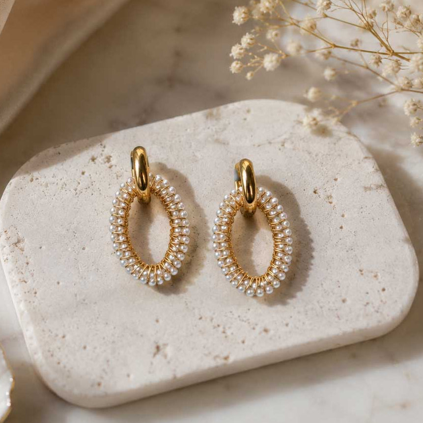 Pearl Glow Hoops – ovale Goldcreolen mit weißen Perlen auf hellem Hintergrund
