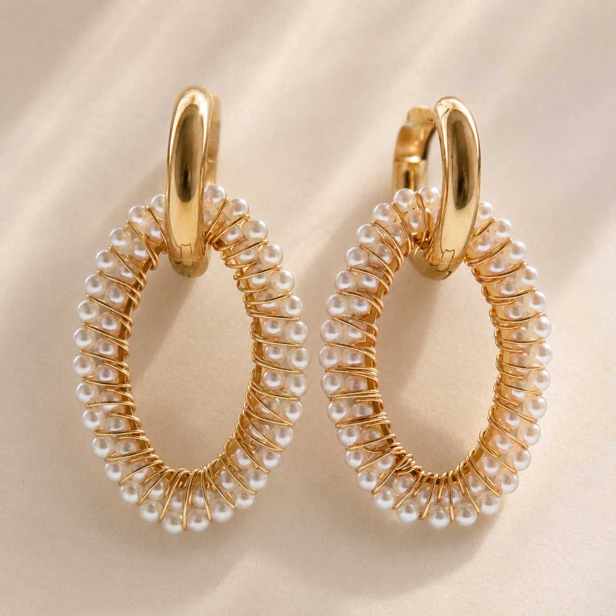 Pearl Glow Hoops von Saltyblush – feminine Goldcreolen mit Perlen, flach auf Oberfläche
