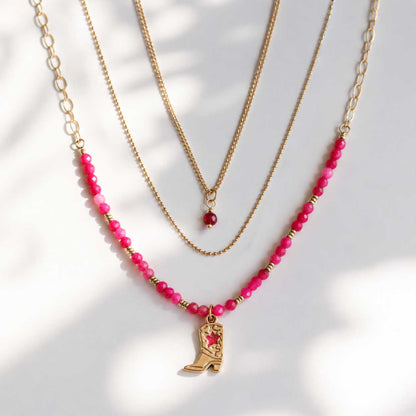 Dreiteiliges goldenes Layering-Halsketten-Set Pink Western mit pinken Perlen, rotem Kristallanhänger und Cowboy-Boot-Charm auf hellem Hintergrund – Saltyblush

