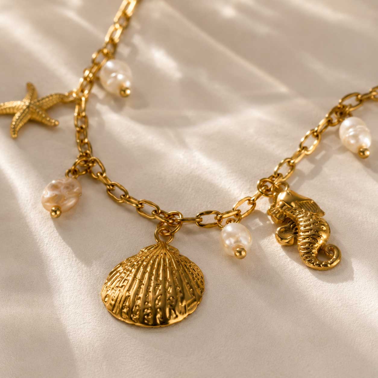 Nahaufnahme maritime Charms – Salt Breeze Halskette von Saltyblush, goldene Muschel, Seestern, Seepferdchen und weiße Perlen an feiner Gliederkette, Detailansicht
