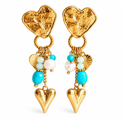 Goldene salty heart Ohrringe mit strukturierten Herzsteckern, türkisfarbenen, mintgrünen und weißen Perlen sowie goldenen Herzanhängern, als Paar vor weißem Hintergrund.
