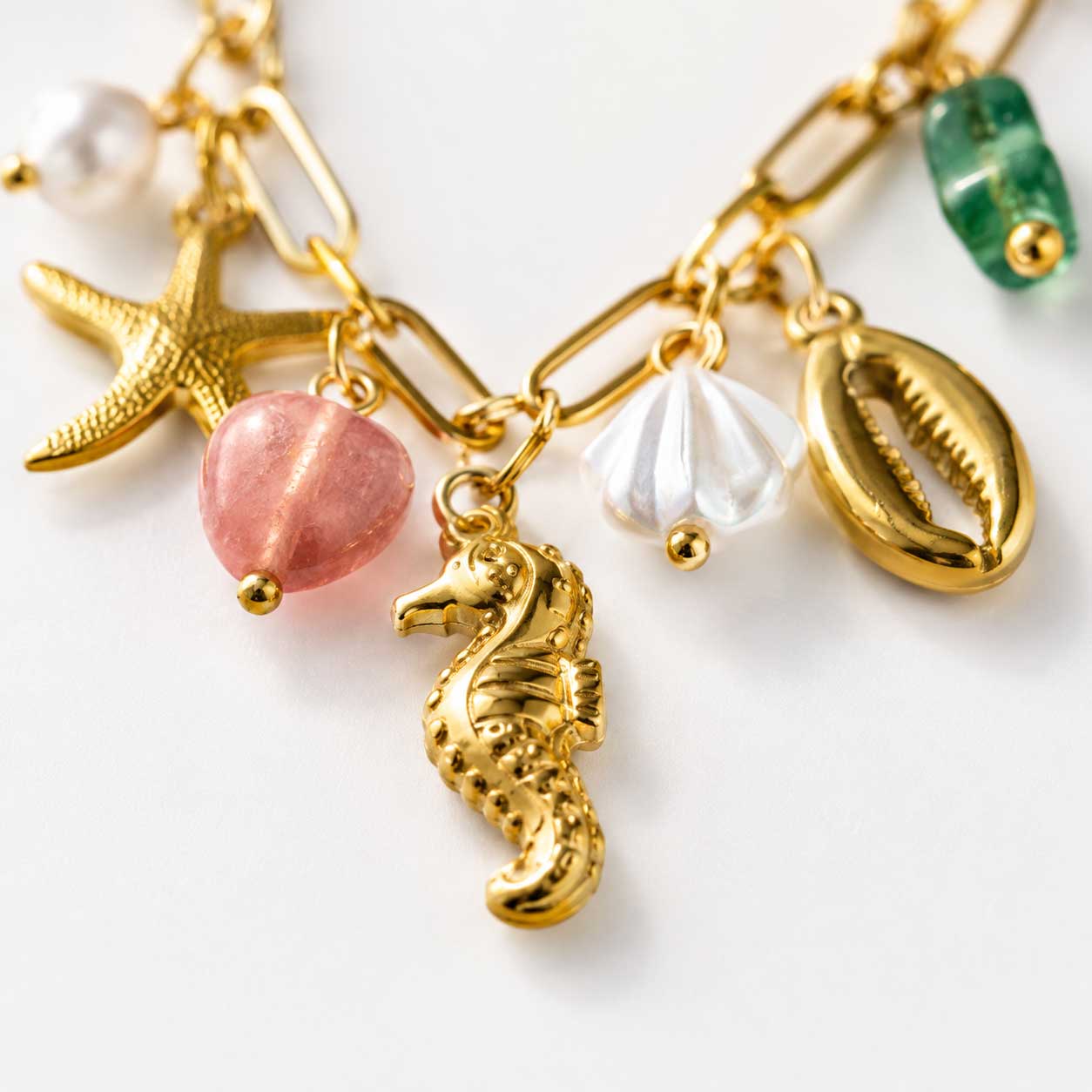 Detailaufnahme sea kiss Halskette – goldener Seepferdchen-Charm, rosa Stein, weiße Muschel und Kaurimuschel aus Edelstahl

