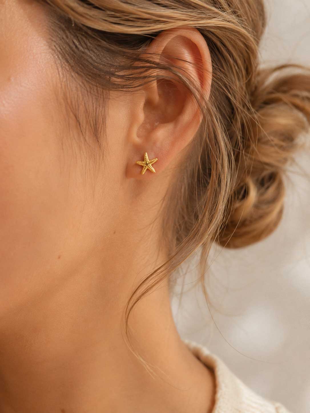 Sea Spirit Ohrringe getragen – goldene Seestern Stecker von Saltyblush am Ohr einer Frau mit blondem Haar, minimalistischer sommerlicher Look
