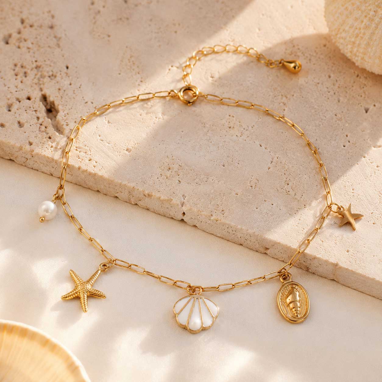 Goldene Fußkette Sea Whisper mit Seestern, Muschel, Perle und Schnecken-Medaillon auf Travertin – Saltyblush