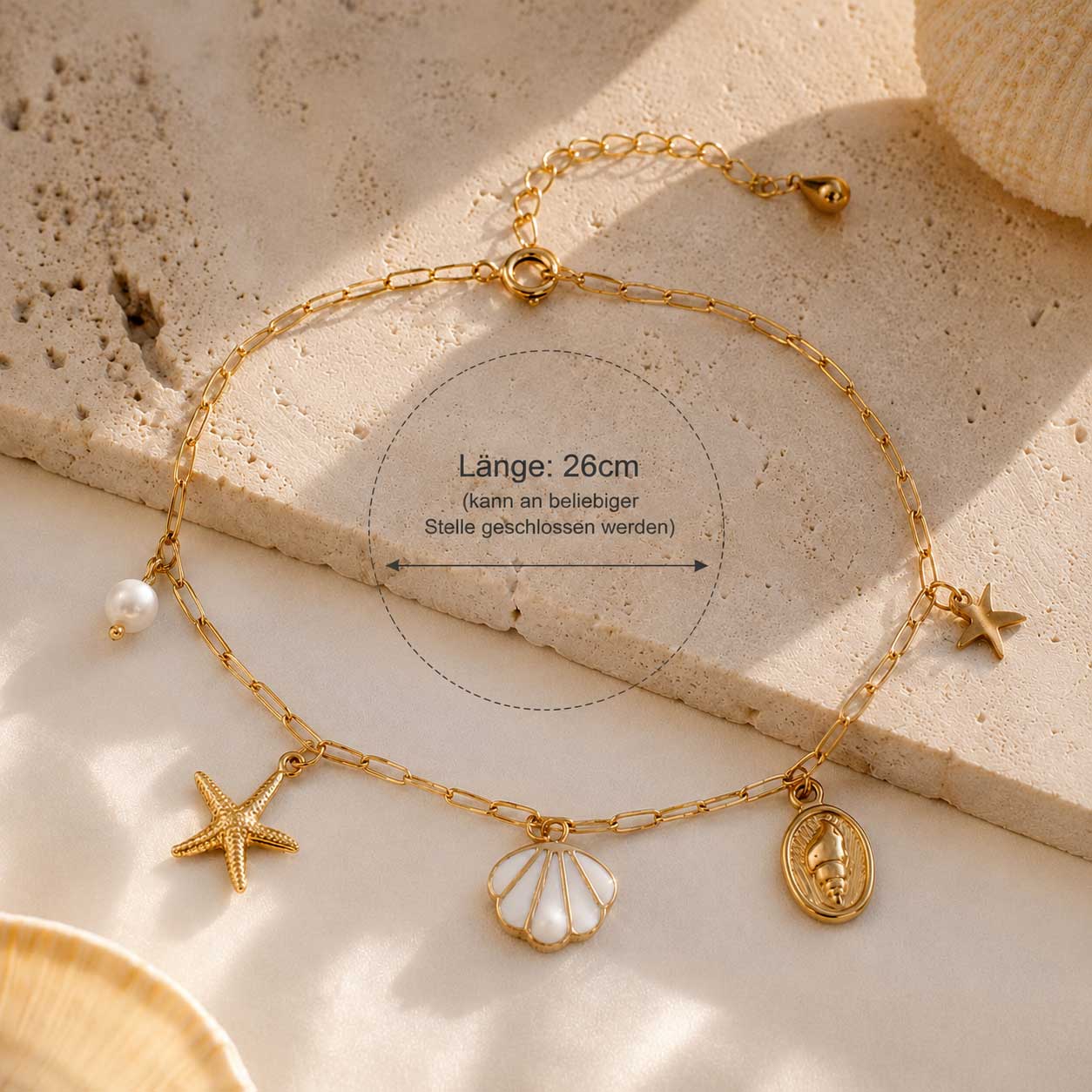 Sea Whisper goldene Fußkette aus Edelstahl mit Längenangabe 26 cm und Meer-Charms auf Travertin – Saltyblush
