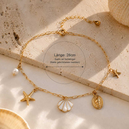 Sea Whisper goldene Fußkette aus Edelstahl mit Längenangabe 26 cm und Meer-Charms auf Travertin – Saltyblush
