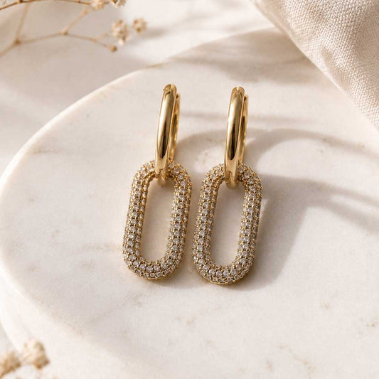 Goldene Creolen mit ovalem Pavé-Anhänger auf Marmortablett mit Trockenblumen – Sparkle Hoops von Saltyblush
