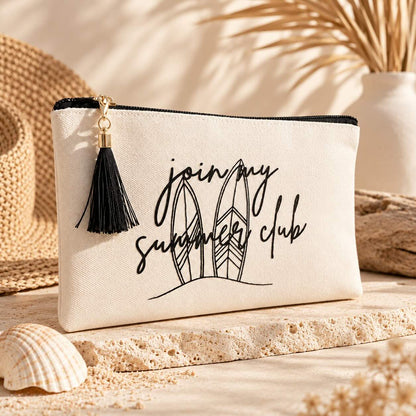 Beige summer club Kosmetiktasche mit schwarzer Quaste, zwei gezeichneten Surfbrettern und Schriftzug „join my summer club“, dekoriert mit Strohhut, Muschel und Trockenblättern.
