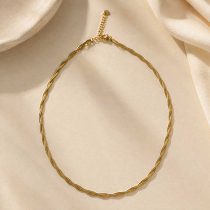 Goldene Halskette Sunny Twist mit gedrehtem Flechtdesign auf cremefarbenem Stoff – Edelstahl, Saltyblush
