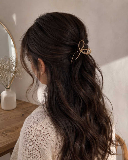 Tide Sunbow Haarklammer im dunklen Haar – goldene Schleifenklammer im Half-Up-Style, elegantes Lifestyle-Foto
