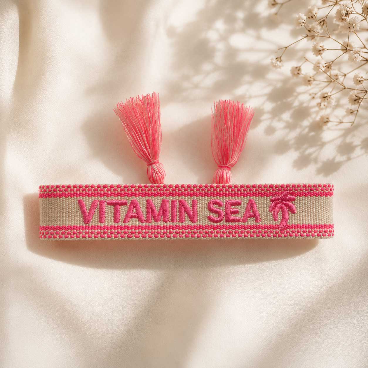 Vitamin Sea Statement Armband aufgeklappt mit zwei pinken Quasten und Palmen-Motiv – Saltyblush
