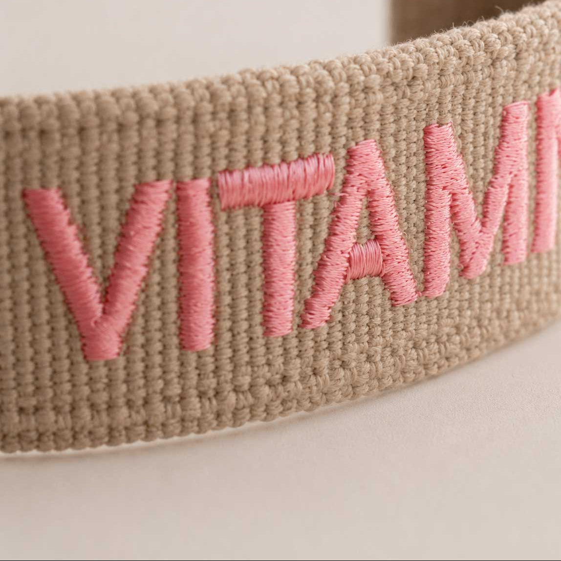 Nahaufnahme gestickter Schriftzug „Vitamin Sea" in Rosa auf beigem Webarmband – Saltyblush Modeschmuck
